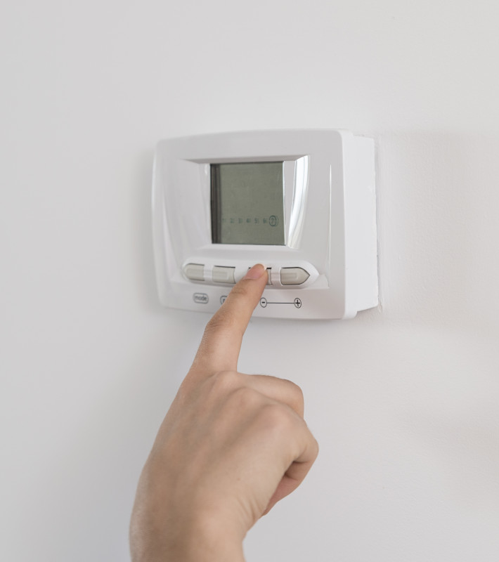 Zeigefinger tippt auf Knopf eines Thermostats